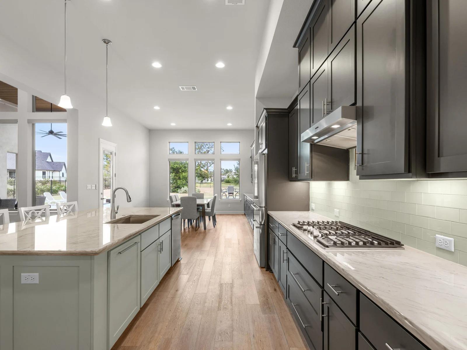 Kitchen with a large island, quartz countertops, dark cabinetry and gas cooktop